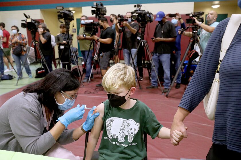 LOS ANGELES, CA - NOVEMBER 03: Felix Johnstone, 7, of Altadena, with mother Caitlin Johnstone, right, receives a child's dose of the Pfizer vaccination from RN Shirley Alfonso at Eugene A. Obregon Park on Wednesday, Nov. 3, 2021 in Los Angeles, CA. The County of Los Angeles, including Supervisor Hilda L. Solis, Dr. Barbara Ferrer, Director of Public Health, and Norma Edith Garcia-Gonzalez, Director of Parks and Recreation, will host a media event kicking off COVID-19 vaccinations for children ages 5-11 in Los Angeles County. The COVID-19 vaccine manufactured by Pfizer and BioNTech is proposed to be given in two 10-microgram (mcg) doses administered 21 days apart. (Gary Coronado / Los Angeles Times)