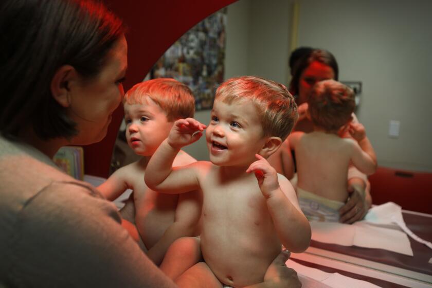 Rachel Gipson entertains her twin boys, Simon and Henry, 2, while waiting to see a pediatrician to talk about immunizations.