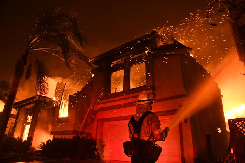 A firefighter battles the flames of the Woolsey fire in an Oak Park neighborhood in the early morning of Nov. 9.