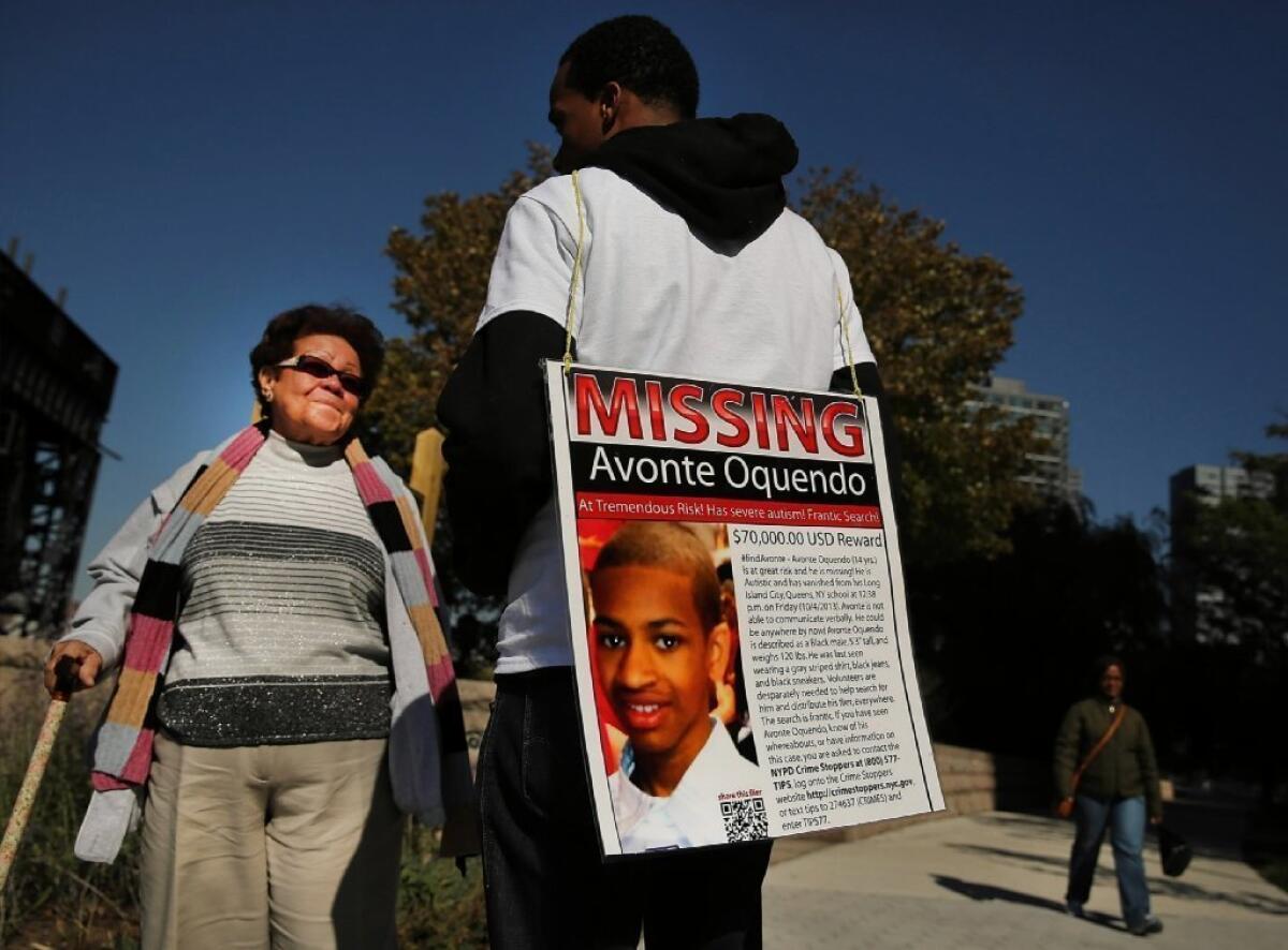 Eric Wright speaks to other pedestrians while wearing a placard with a picture of a missing autistic 14-year-old named Avonte Oquendo on Oct. 21, 2013, in New York City's Queens borough. Now, remains found in the East River are said by police to be Oquendo's.