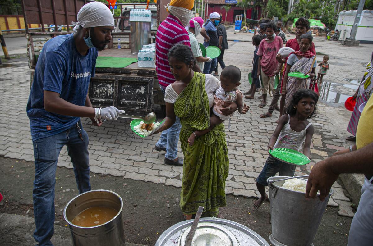 Homeless people stand in a queue to receive free food distributed by the Sikh community in Gauhati, India. 