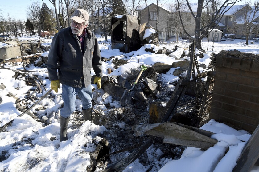 FILE - Rex Hickman sifts through the rubble of his burned home in Louisville, Colo., on Sunday, Jan. 2, 2022. Hickman, who had lived in the home with his wife for 23 years, found his safe, but little could be salvaged other than a few gold and silver coins. In Colorado and other states hit by natural disasters this year, the pandemic has injected extra uncertainty and created more obstacles for families trying to rebuild. (AP Photo/Thomas Peipert, File)