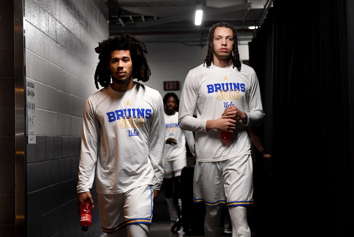 UCLA's Tyger Campbell, left, and Mac Etienne walk to the court for Thursday's first-round game