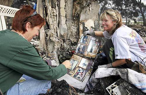 Kris Hoyt, left, celebrates a find with friend Melissa Puyot, who digs out cherished mementos from her burned-out home in Ramona.