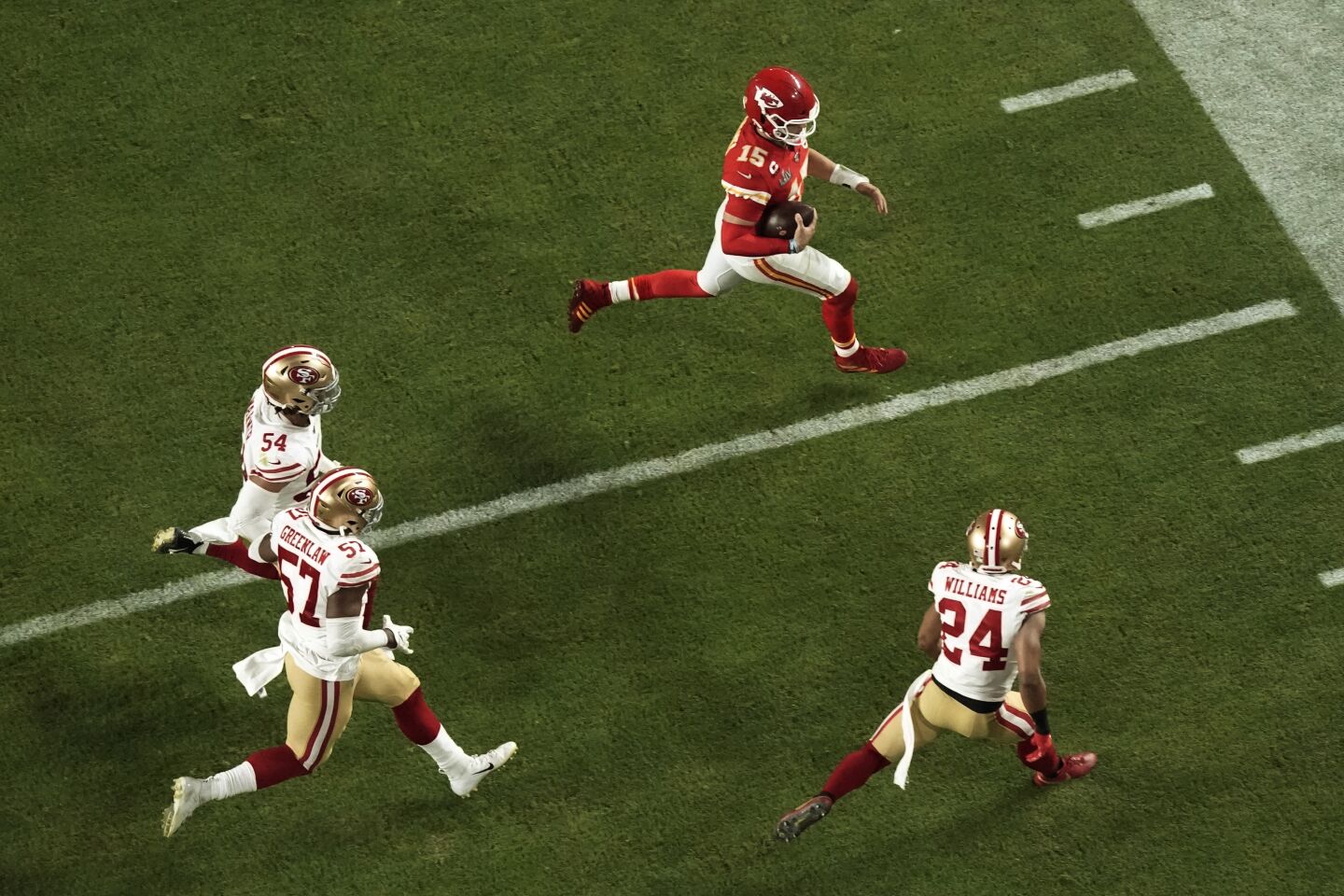 Kansas City Chiefs quarterback Patrick Mahomes, top, is chased by San Francisco 49ers defenders K'Waun Williams (24), Dre Greenlaw (57), and Fred Warner (54) during the second half of Super Bowl LIV.