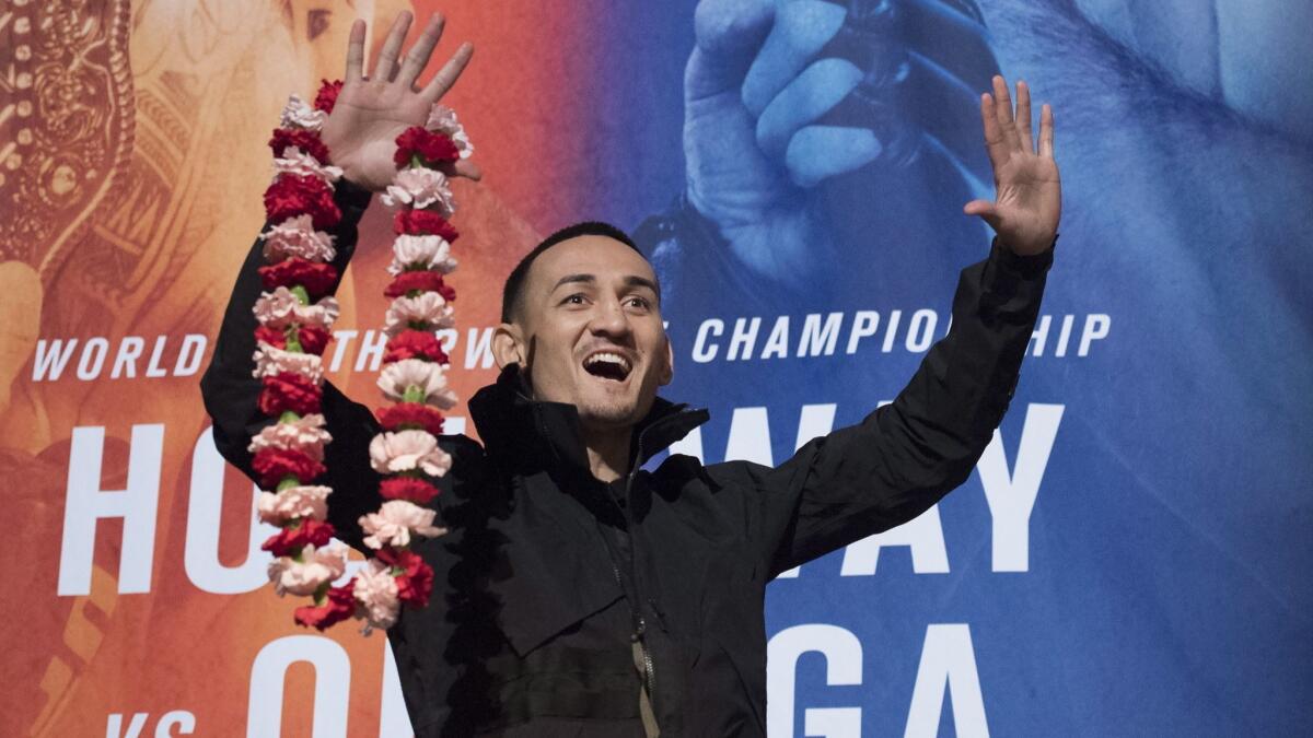 UFC featherweight champion Max Holloway reacts to the crowd during at a news conference on Wednesday,