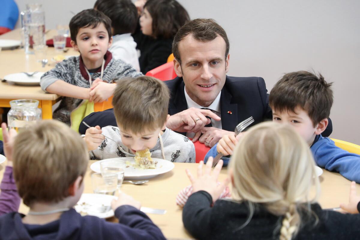 French President Emmanuel Macron meets pupils at a school canteen in Saint-Sozy, southwestern France. 