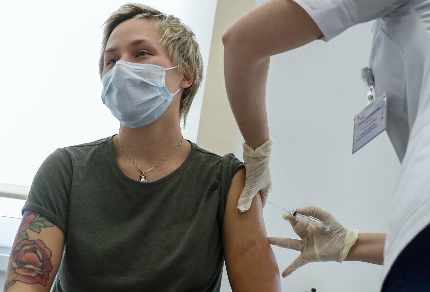 Russian medical worker, right, administers a shot of Russia's Sputnik V coronavirus vaccine in Moscow, Russia, Saturday, Dec. 5, 2020. Thousands of doctors, teachers and others in high-risk groups have signed up for COVID-19 vaccinations in Moscow starting Saturday, a precursor to a sweeping Russia-wide immunization effort. (AP Photo/Pavel Golovkin)