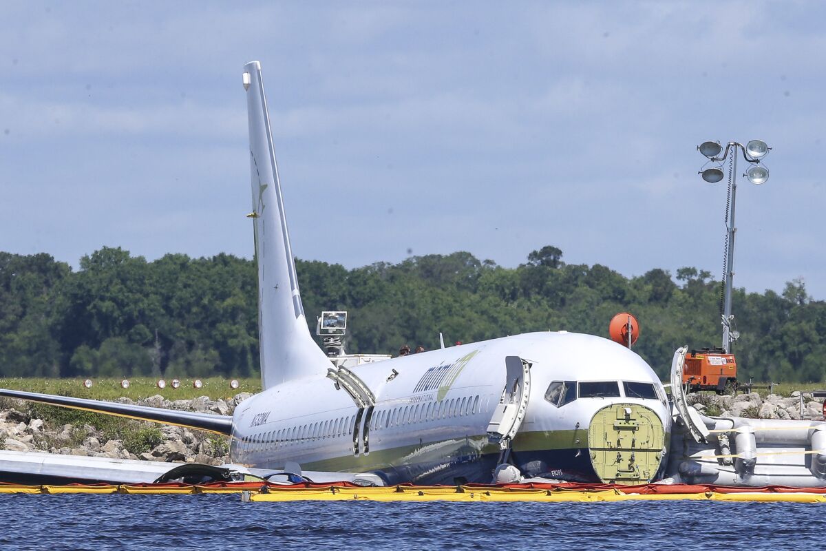 FILE - In this May 4, 2019, file photo, a charter plane carrying 143 people and traveling from Cuba to north Florida sits in a river at the end of a runway in Jacksonville, Fla. Investigators say the loss of braking power on a rain-soaked flooded runway caused a cargo plane chartered by the Pentagon to slide into a Florida river in 2019, the National Transportation Safety Board said Wednesday, AUg. 4, 2021. (AP Photo/Gary McCullough, File)