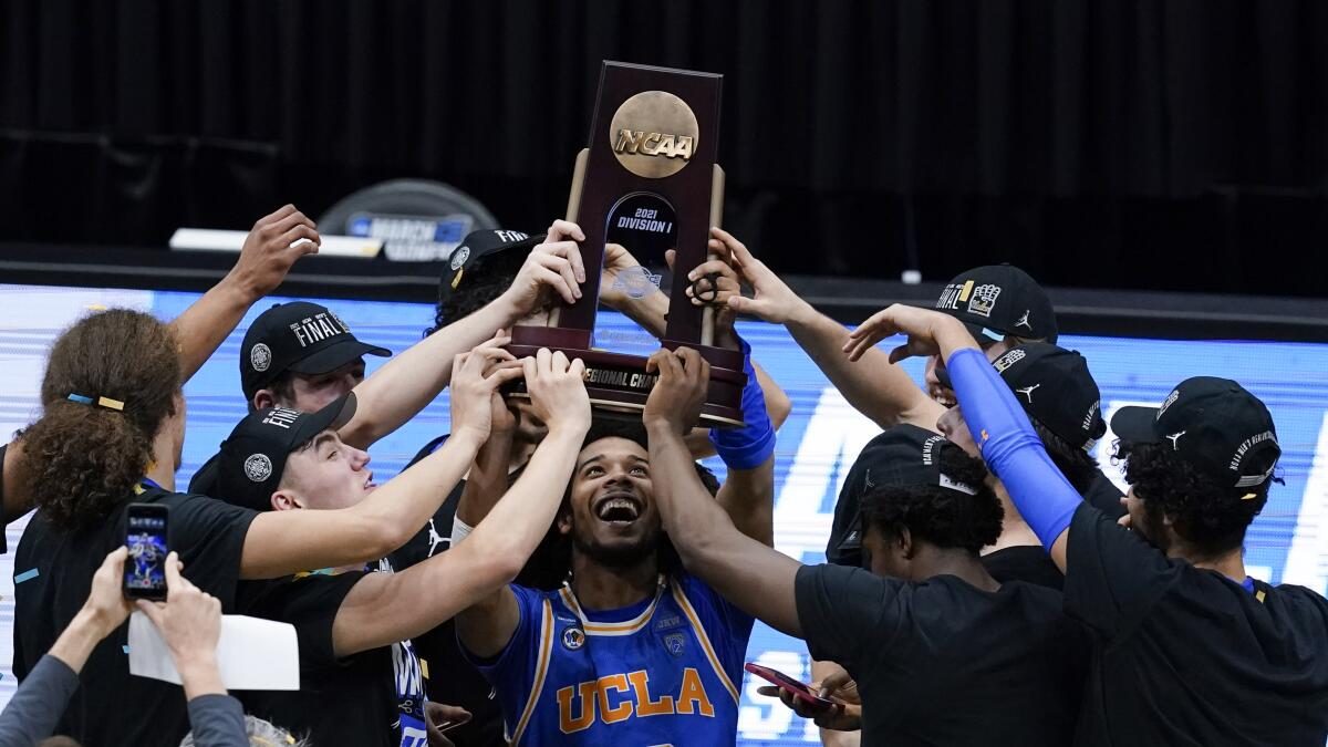UCLA guard Tyger Campbell (10) celebrates with teammates after an Elite 8 game against Michigan in the NCAA men's college basketball tournament at Lucas Oil Stadium, Wednesday, March 31, 2021, in Indianapolis. UCLA won 51-49. (AP Photo/Darron Cummings)