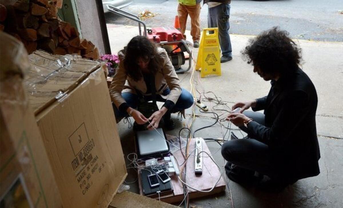 Two people try to charge their laptops and cellphones from a generator in New York.