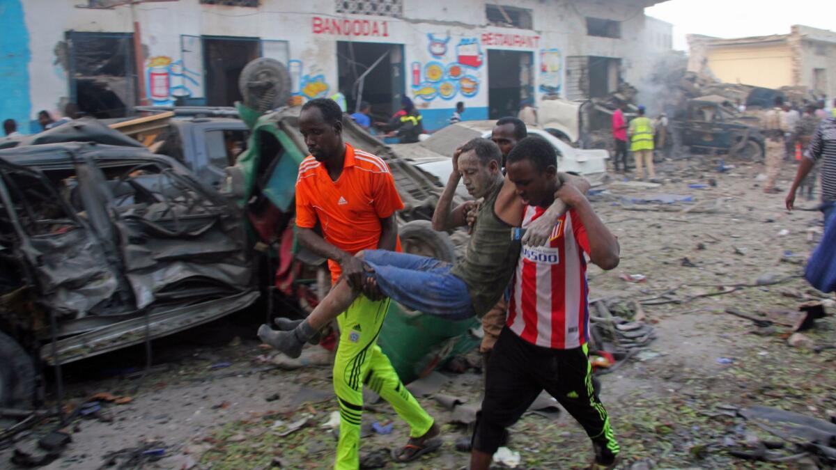 Somalis carry away a man injured when a car bomb exploded outside a hotel in Mogadishu, Somalia, on Oct. 28, 2017.