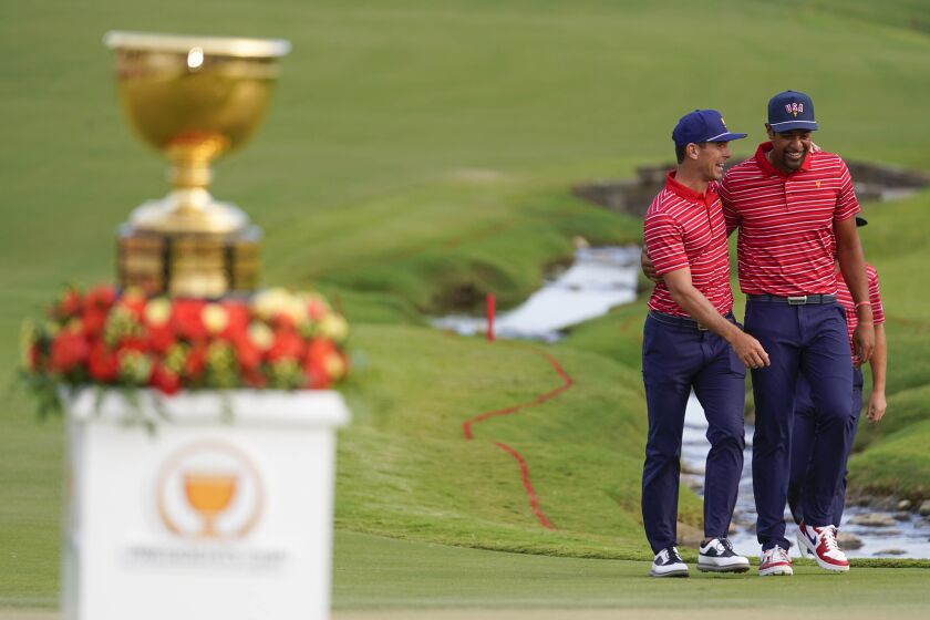 Billy Horschel, left, walks with Tony Finau after the USA team defeated the international team in match play at the Presidents Cup golf tournament at the Quail Hollow Club, Sunday, Sept. 25, 2022, in Charlotte, N.C. (AP Photo/Julio Cortez)