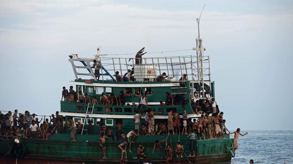 Rohingya migrants bring back food supplies dropped by a Thai army helicopter after jumping into the sea to collect them.