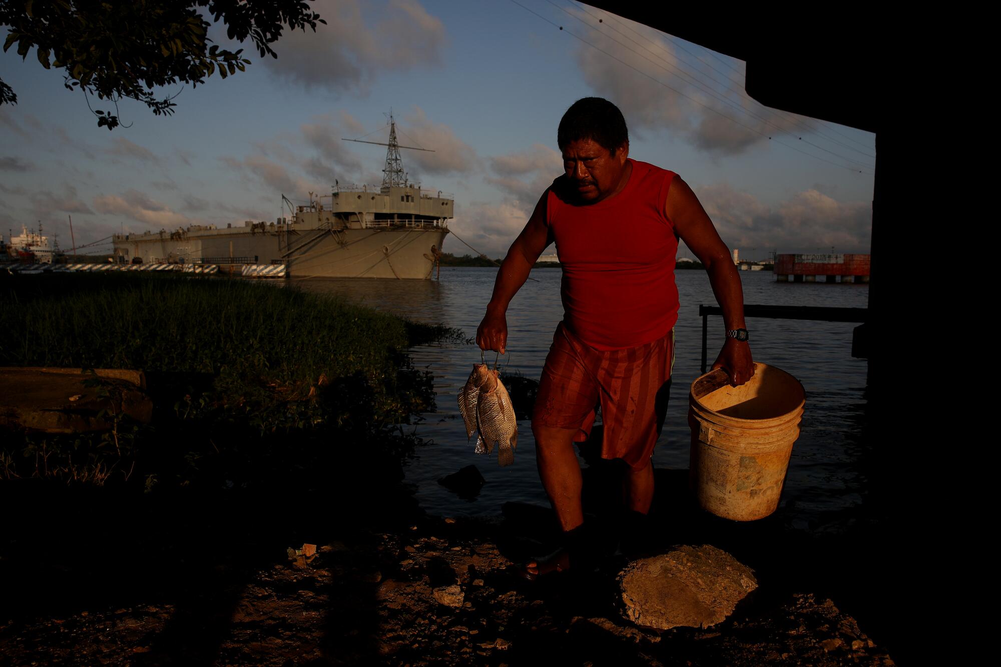 A man carries freshly caught fish near a port.