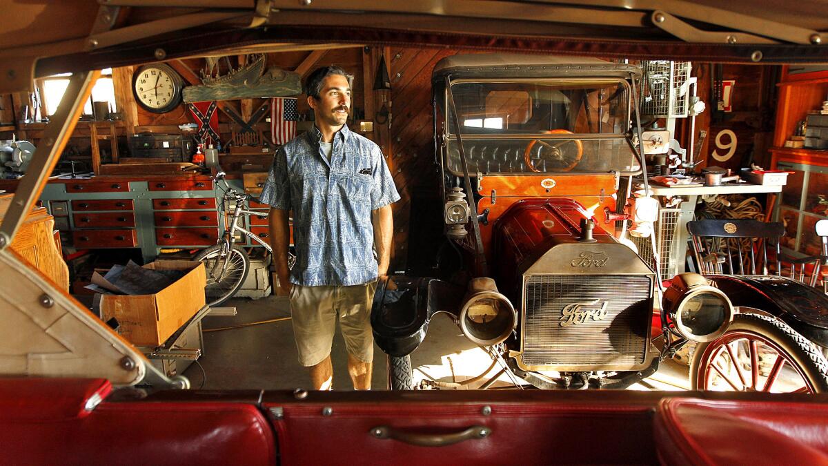 Dennis Holland Jr. stands inside his father's barn in Newport Beach, where his late dad worked on numerous side projects, including a Ford Model T and a 72-foot sailboat.