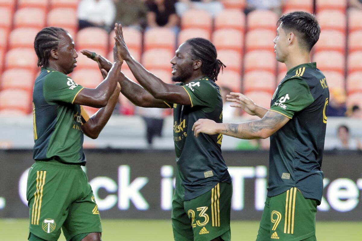 Portland Timbers' Diego Chara, left, Yimmi Chara, center, and Felipe Mora celebrate Yimmi Chara's goal against the Houston Dynamo during the first half of an MLS soccer match Friday, Sept. 3, 2021, in Houston. (AP Photo/Michael Wyke)