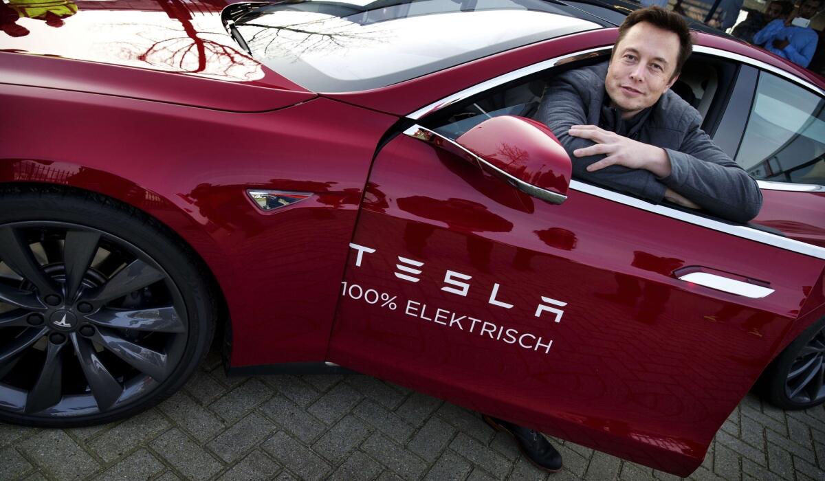 Elon Musk, co-founder and CEO of American electric vehicle manufacturer Tesla Motors, poses with a Tesla during a visit to Amsterdam.