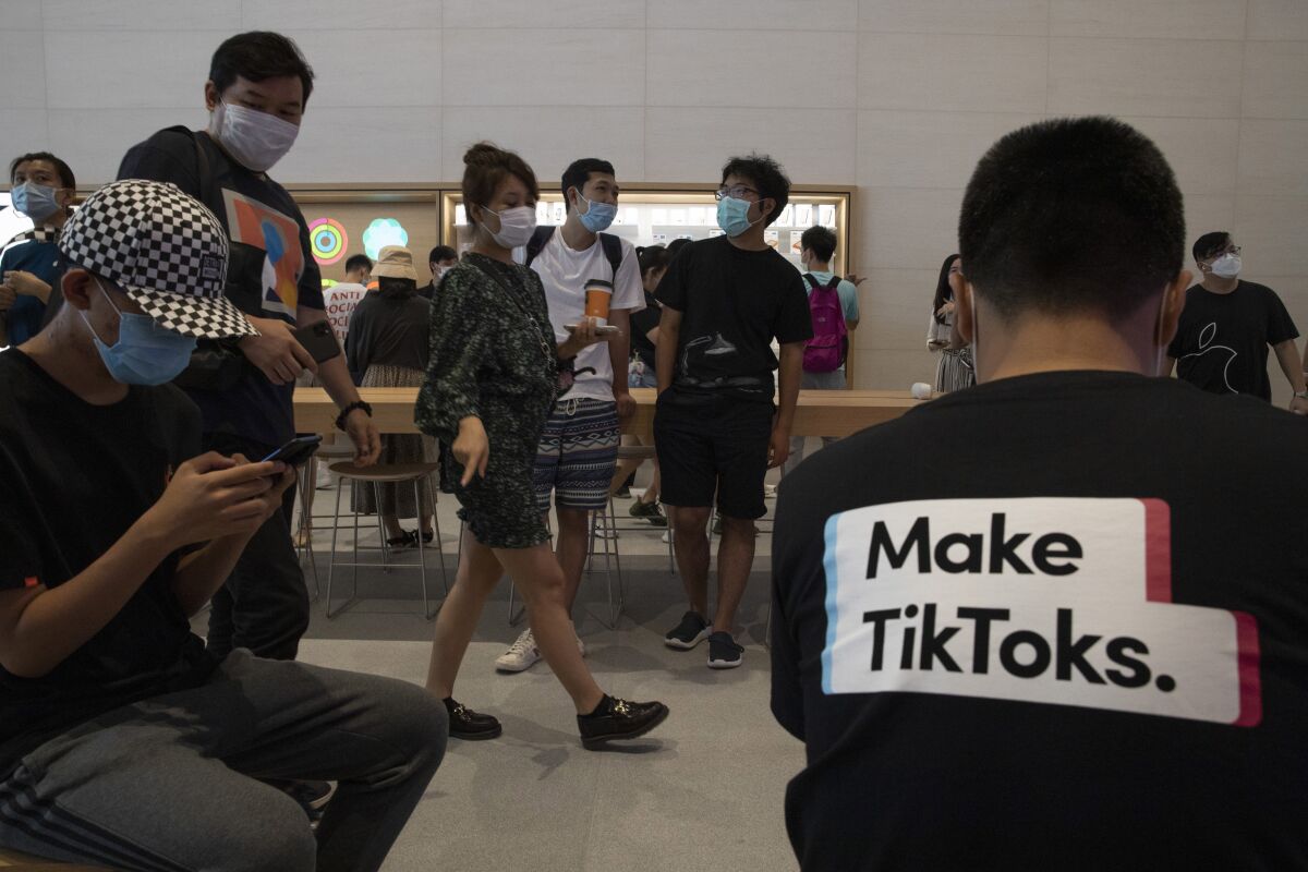 A visitor to an Apple store wears a t-shirt promoting Tik Tok in Beijing on Friday, July 17, 2020. U.S. President Donald Trump on Thursday, Aug 6, 2020 ordered a sweeping but unspecified ban on dealings with the Chinese owners of consumer apps TikTok and WeChat, although it remains unclear if he has the legal authority to actually ban the apps from the U.S. (AP Photo/Ng Han Guan)