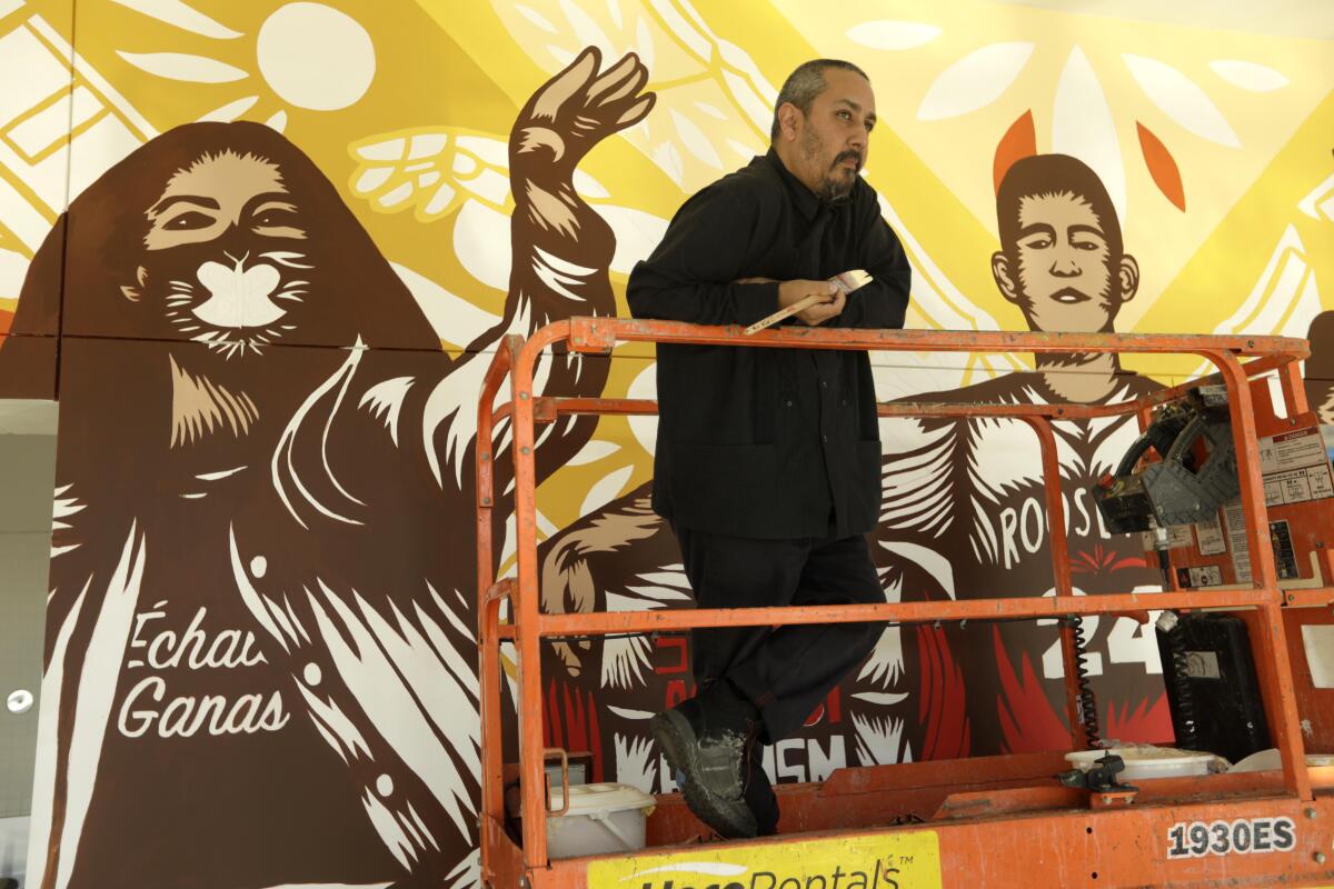 Artist Alfonso Aceves in front of a mural