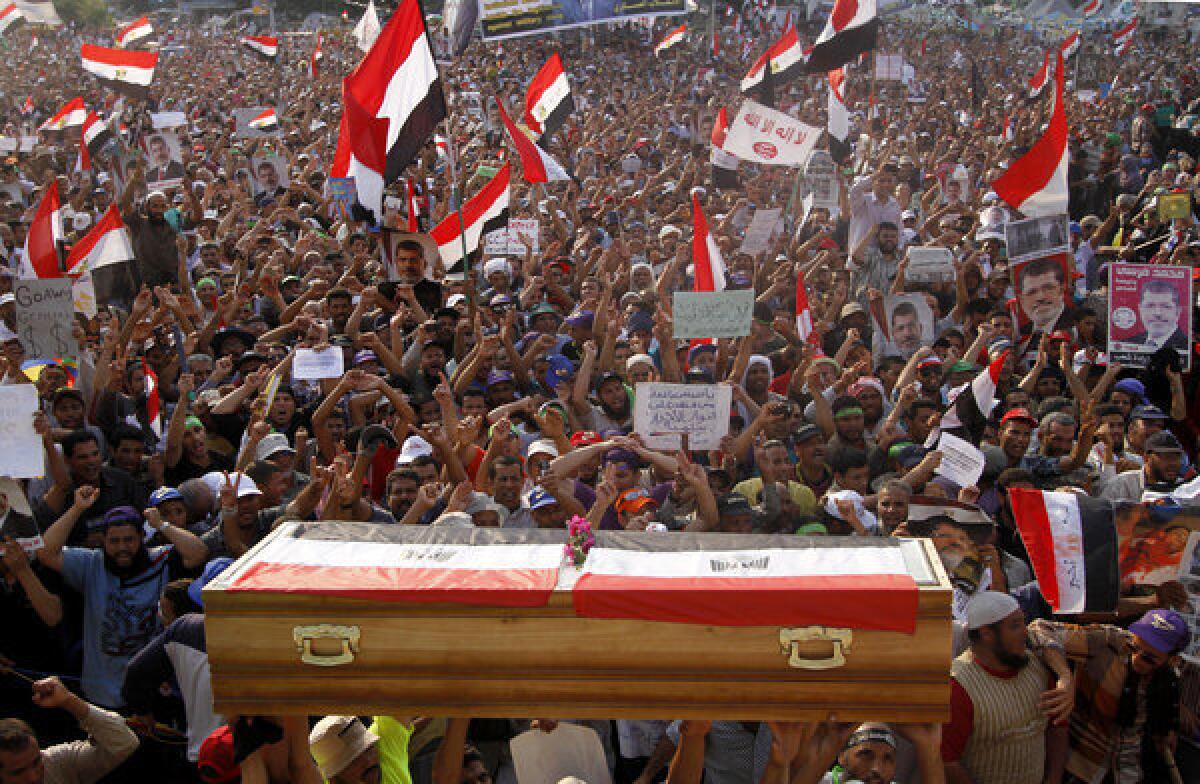 Supporters of ousted President Mohamed Morsi hold up a symbolic coffin during a rally in Cairo, Egypt, to protest the killing of more than 50 people by the Egyptian military and police.