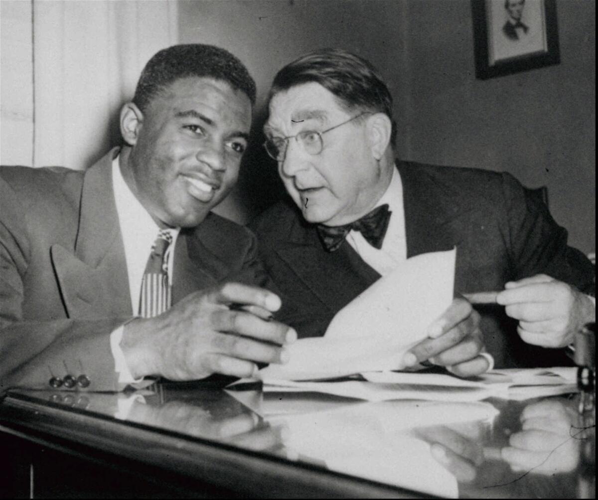 Brooklyn Dodgers' Jackie Robinson, left, and Dodgers President Branch Rickey look over Robinson's contract.