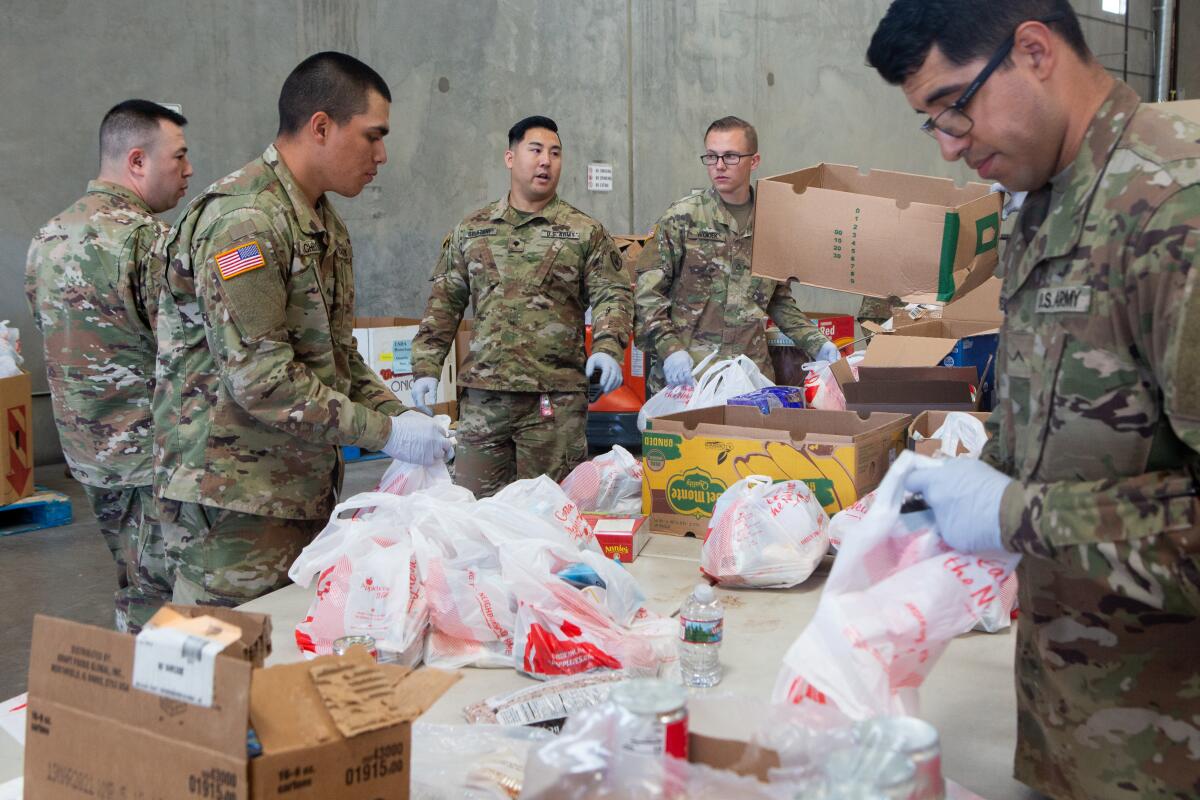 Members of the 315 Vertical Construction Company unit  of the California National Guard pack bags of food at the FIND Food Bank in Indio.