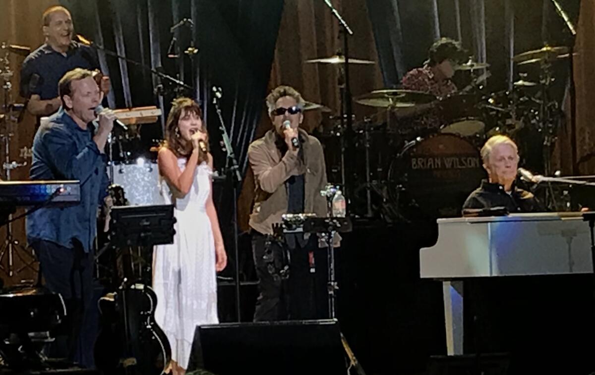 Brian Wilson, right, was joined by band member Matt Jardine, left, and She & Him duo Zooey Deschanel and M. Ward, on Thursday at the Greek Theatre in Los Angeles.