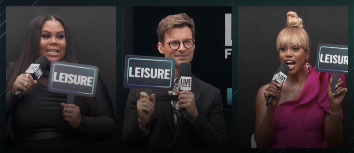 E! hosts Nina Parker, Brad Goreski, and Laverne Cox hold signs predicting nominees will don "leisure" wear.