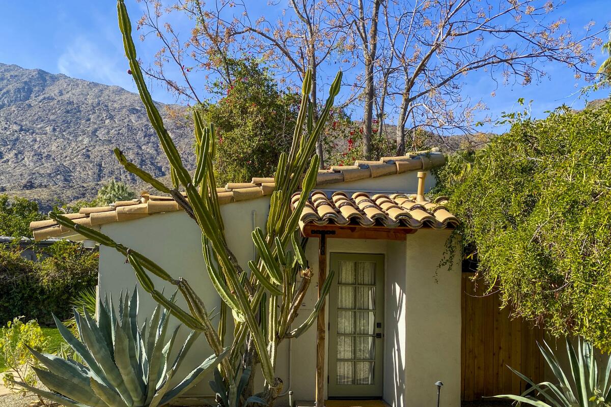 A casita with a Spanish tile roof in a desert landscape with mountains behind