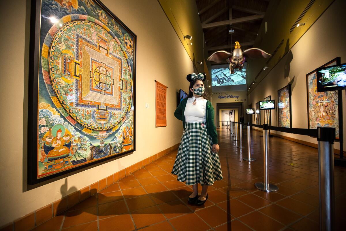 A 13-year-old visitor stands in front of a mural at Bowers Museum in Santa Ana.