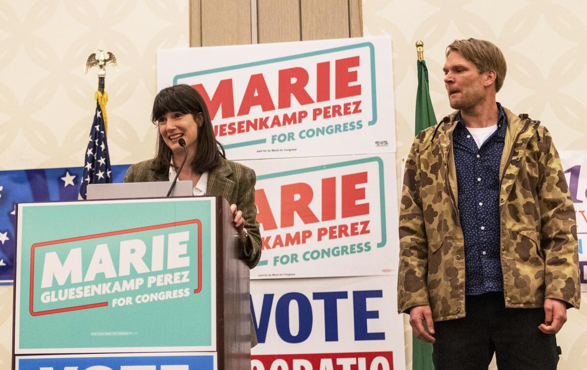 Marie Gluesenkamp Perez, left, speaks to a crowd of supporters while her husband Dean Gluesenkamp looks at during the Clark County Democrats election night watch party at a hotel in Vancouver, Wash., Tuesday, Nov. 8, 2022. (Taylor Balkom/The Columbian via AP)