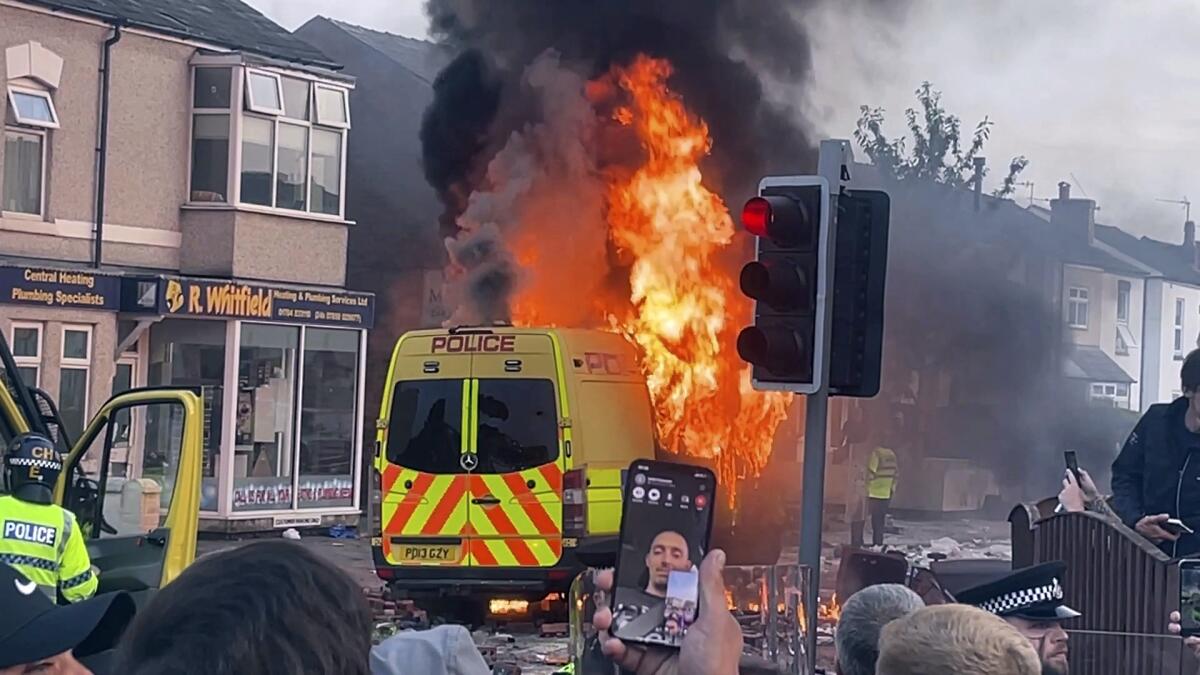 Una camioneta policial arde mientras una multitud choca con al policía
