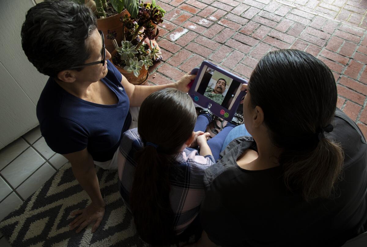 Teresa Gonzalez, left, with her granddaughter Camila, 8, and daughter Mabel, FaceTime with Gonzalez's husband, Francisco.