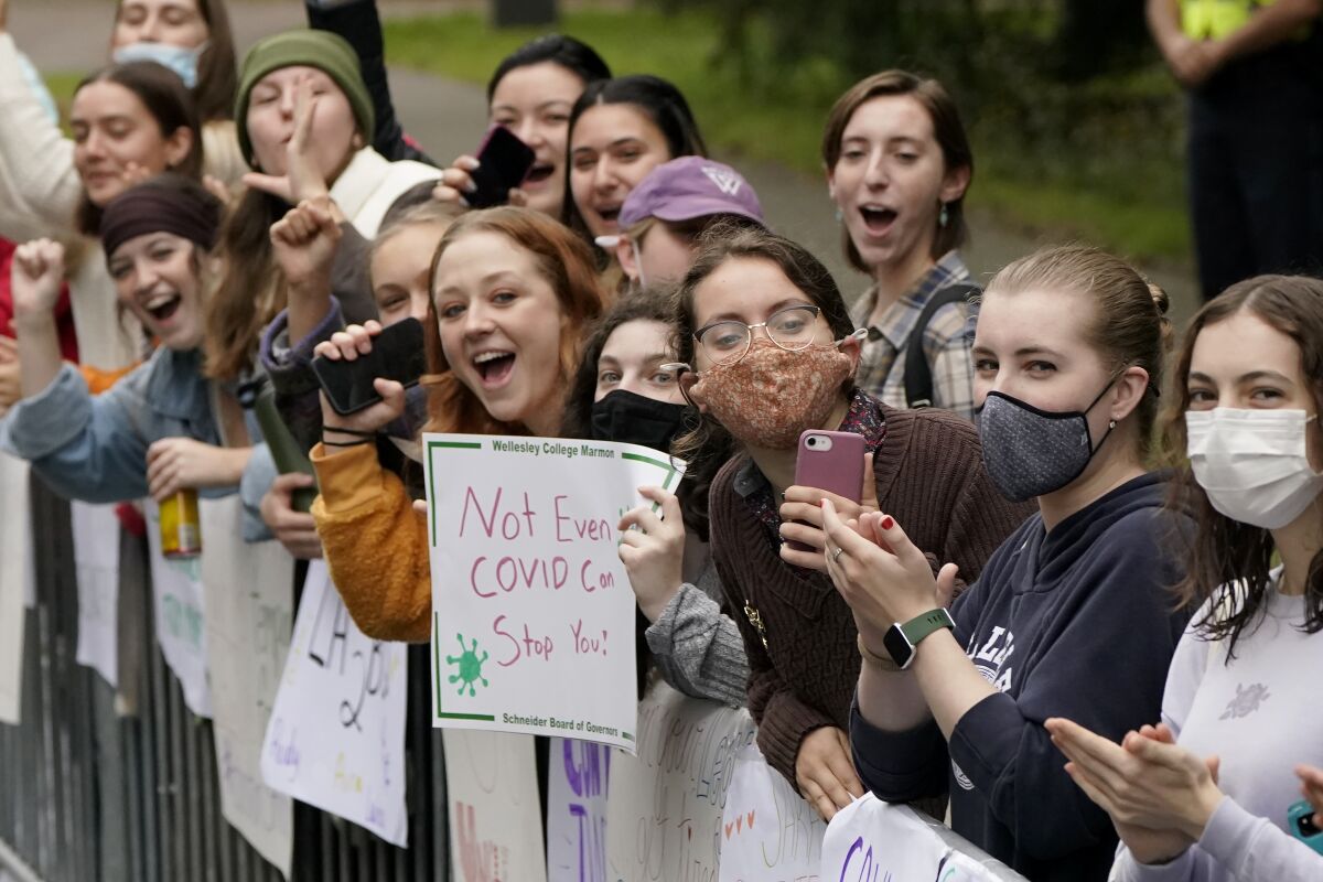 Women displays signs and cheer in front Wellesley College, in Wellesley, Mass., as a runner passes during the 125th Boston Marathon, Monday, Oct. 11, 2021. (AP Photo/Steven Senne)