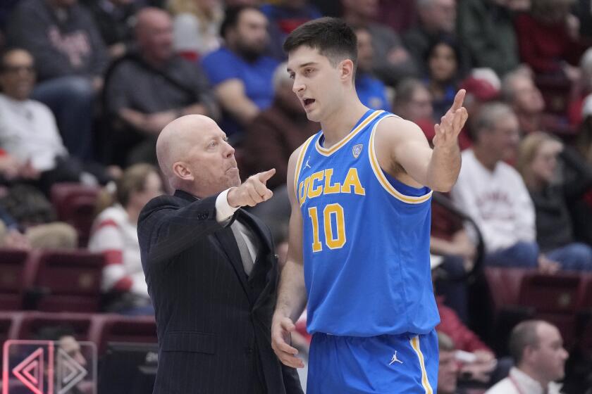 UCLA head coach Mick Cronin, left, gestures while talking to guard Lazar Stefanovic.