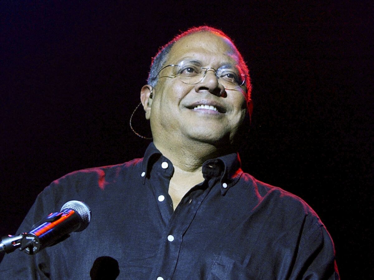 Pablo Milanés smiles in front of a microphone.
