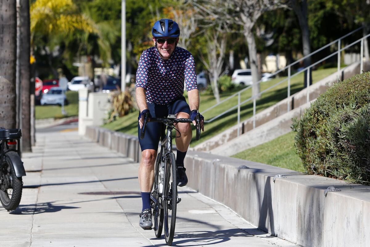Dr. Brian Dozer, center, the president of Vital Link, rides his bicycle to Laguna Beach High School on Friday.