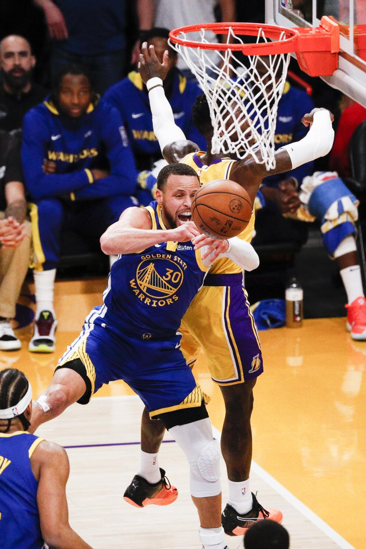 Warriors guard Stephen Curry, front, loses control of the ball while going up for a shot against Lakers guard Dennis Schroder