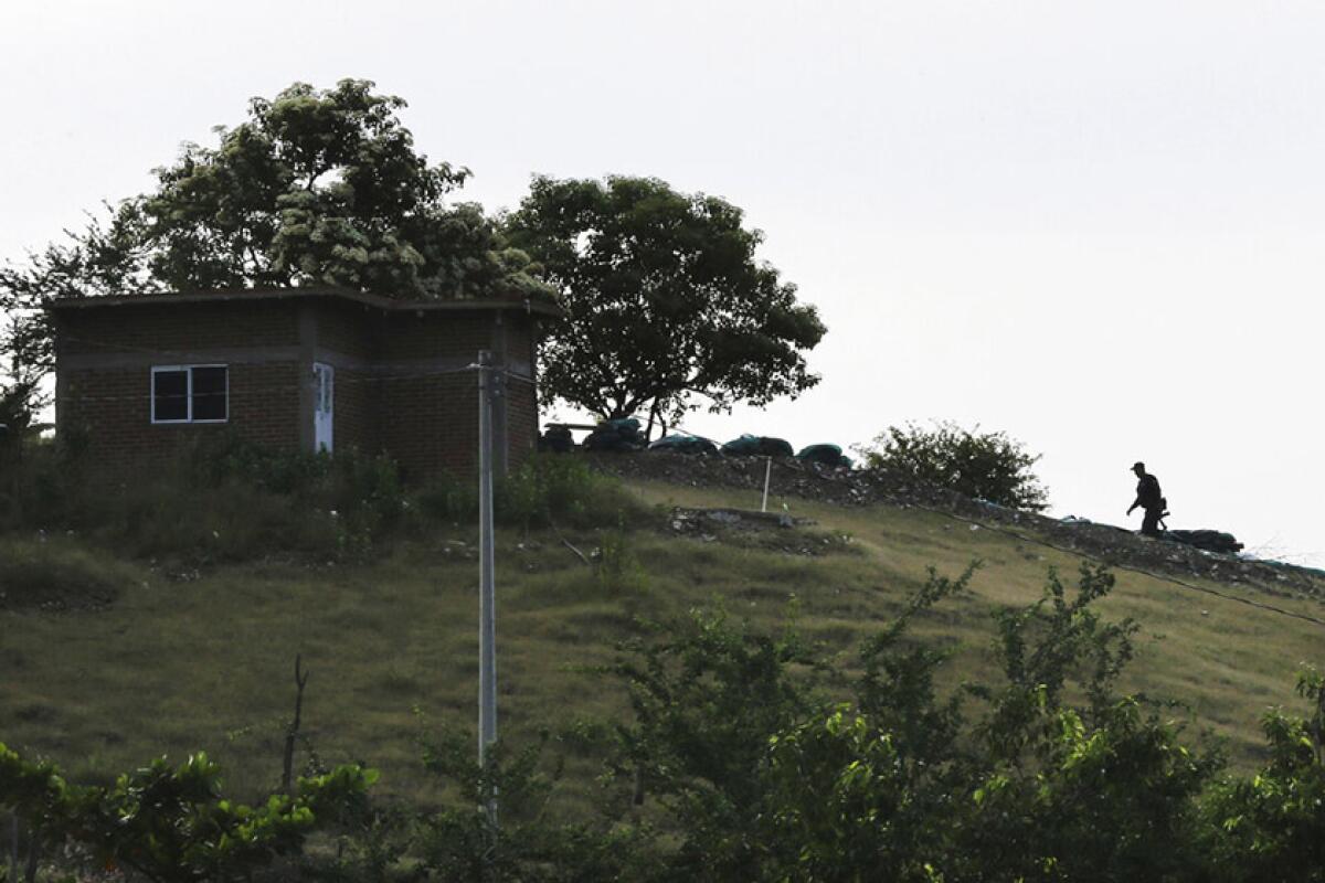 A heavily armed vigilante heads to a sniper post atop a hill on the outskirts of Tepalcatepec, Mexico. The vigilantes guard against incursions by the Jalisco cartel.