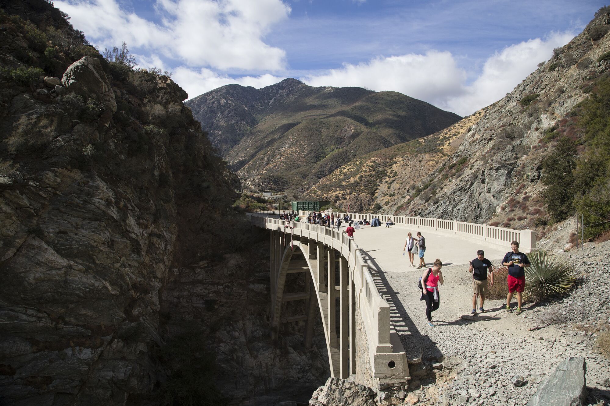 Hikers walk over the Bridge to Nowhere as bungee jumpers harness up in the background.