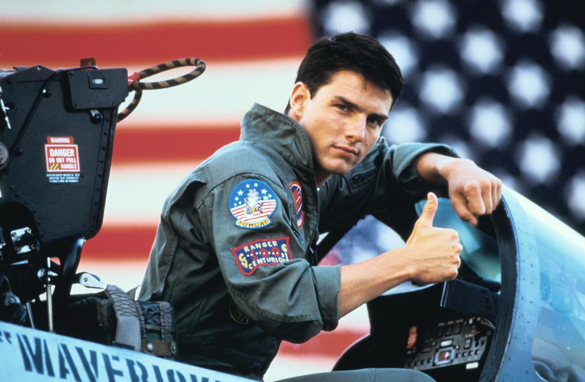 Tom Cruise as Maverick in the movie "Top Gun," giving a thumbs-up from the open cockpit of a fighter jet