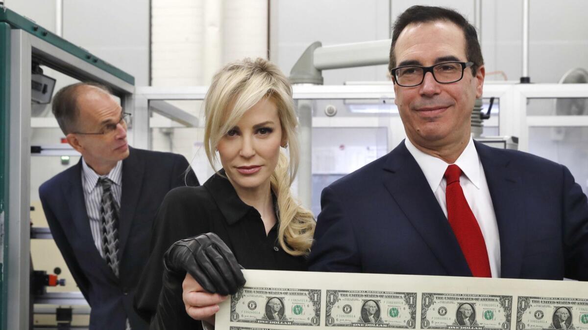 Sheets of greenbacks don't equal economic growth: Treasury Secretary Steven T, Mnuchin, right, and his wife Louise Linton hold a sheet of new $1 bills, the first currency notes bearing his signature, at the Washington mint in November 2017.