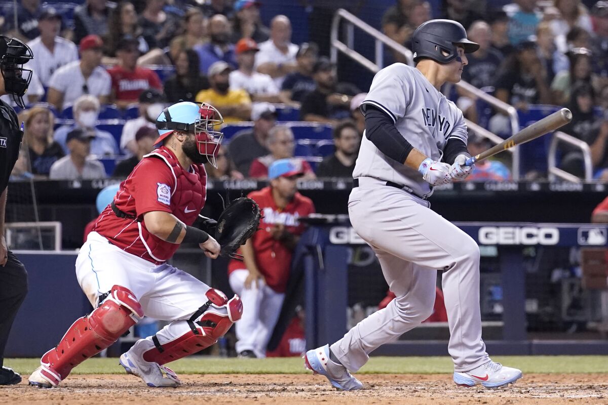 New York Yankees' Anthony Rizzo, right, watches after hitting a single to score Brett Gardner during the eighth inning of a baseball game, Sunday, Aug. 1, 2021, in Miami. Marlins catcher Sandy Leon, second from right, looks on. (AP Photo/Lynne Sladky)