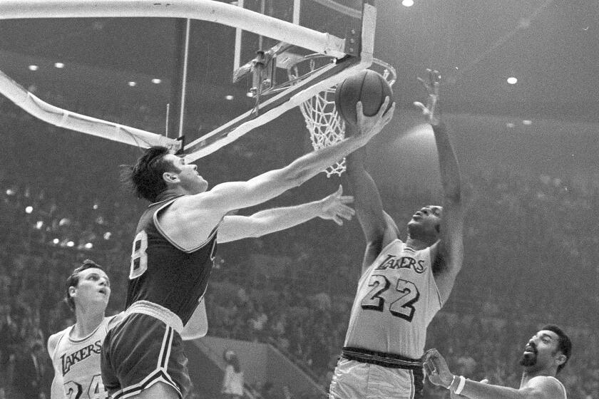 The Boston Celtics' Bailey Howell, left, whirls with a reverse lay up against the Lakers at Los Angeles