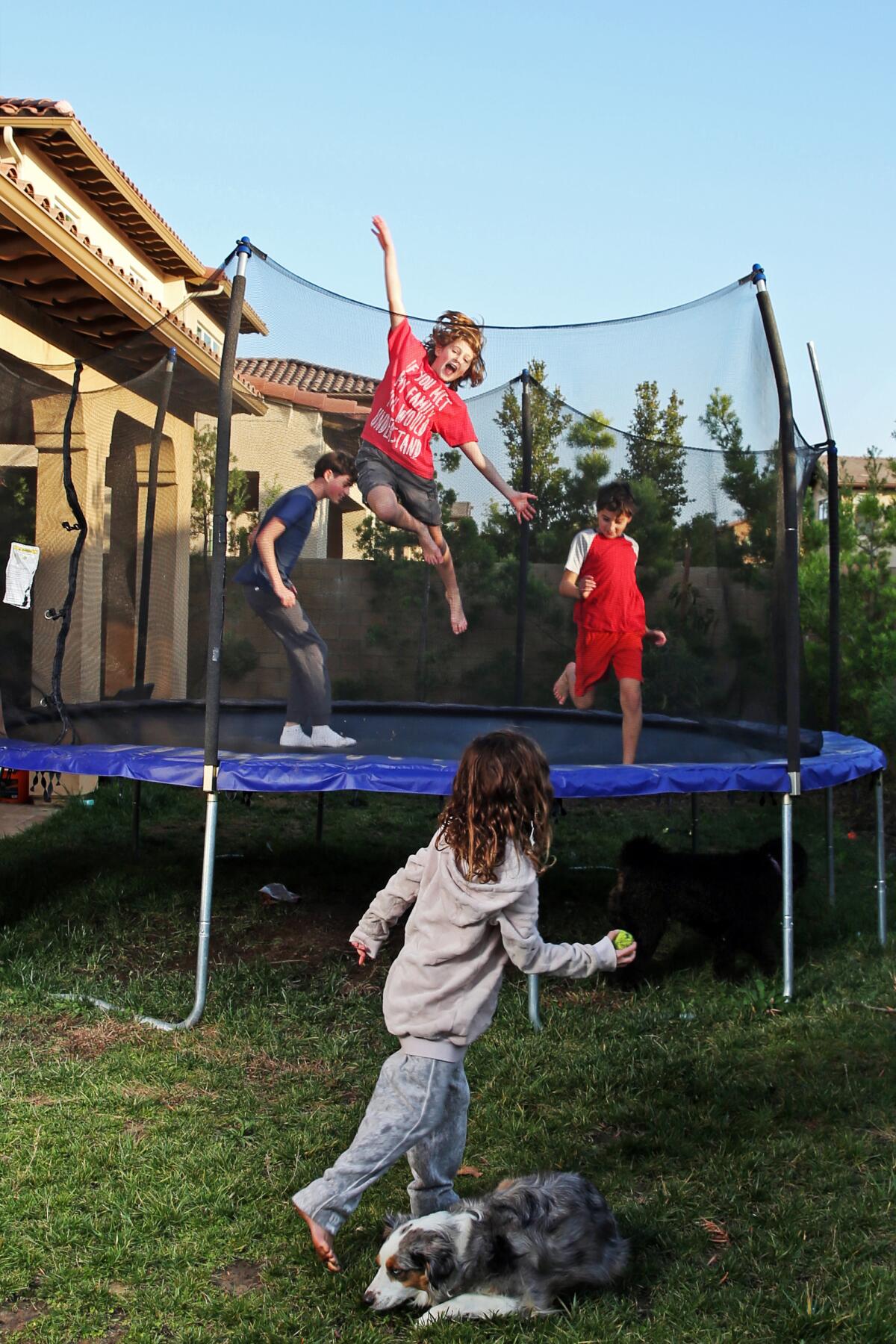 Kids play on a backyard trampoline. 