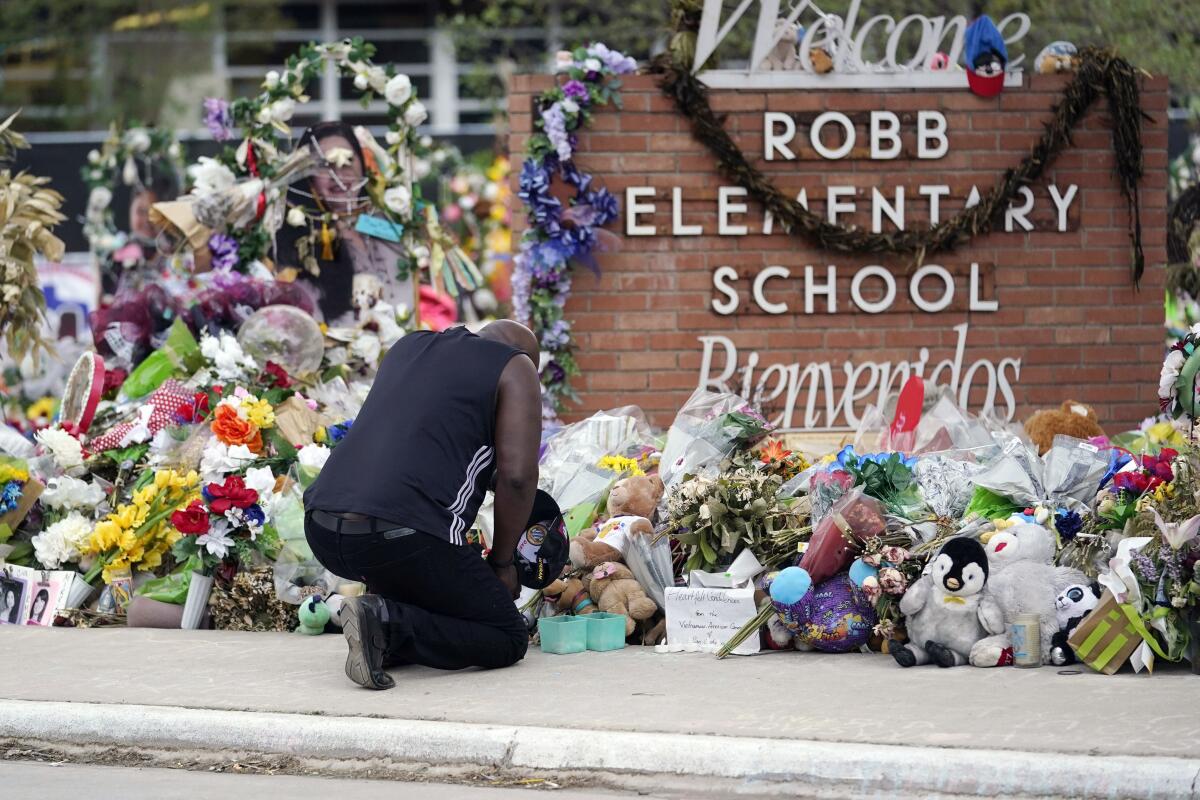 Man kneels and pays respects at makeshift memorial around school sign