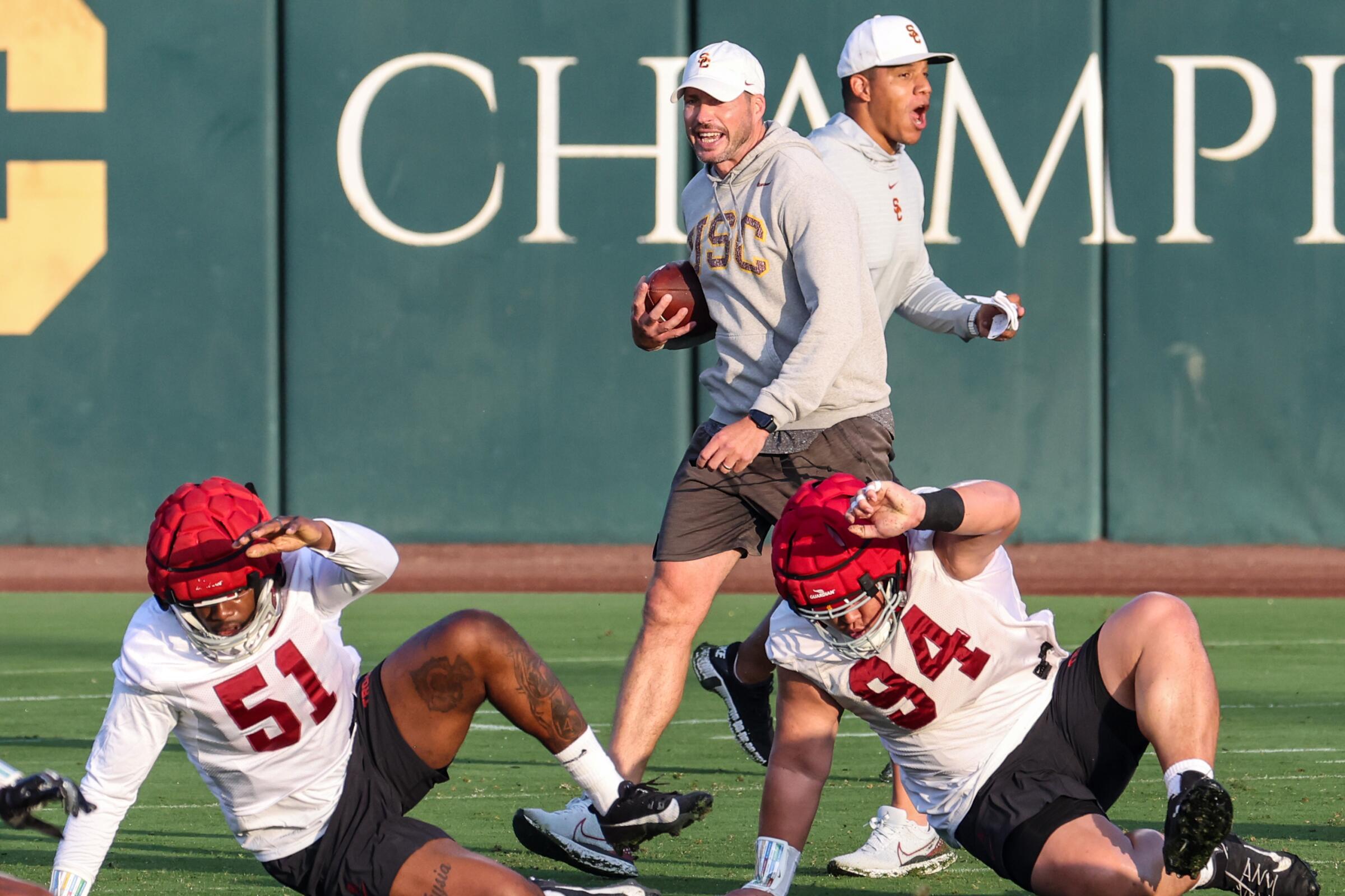 USC defensive coordinator Alex Grinch, left, and assistant Donte Williams bark instructions during a training camp drill.