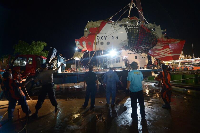 The recovered tail section of AirAsia Airbus Flight 8501 is prepared to be loaded onto a truck at port in Kumai, Indonesia, on Sunday.