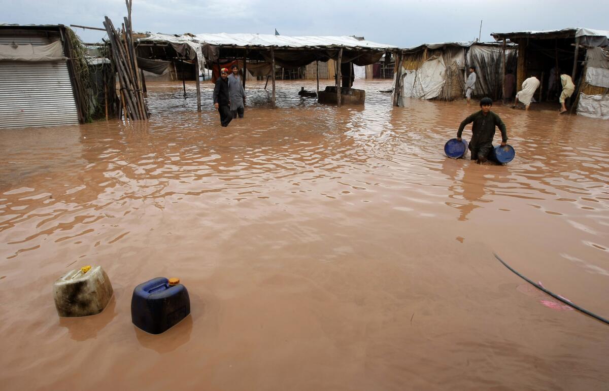 Pakistani villagers collect their belongings after flash flooding on the outskirts of Peshawar on April 3, 2016.